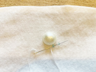 縫い付けたビーズにもう一度針を通してから2粒目のビーズを通します。
